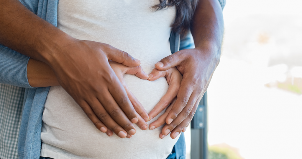 Woman and mans hands on pregnant stomach