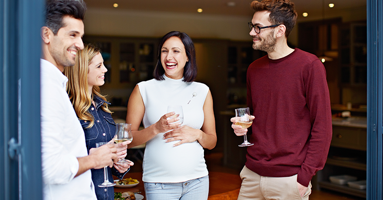 Friends hanging out having drinks while pregnant friend has water.