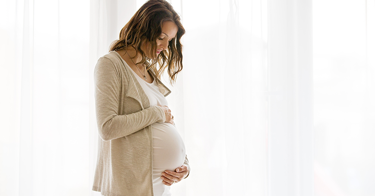 Pregnant woman looking down at her stomach.