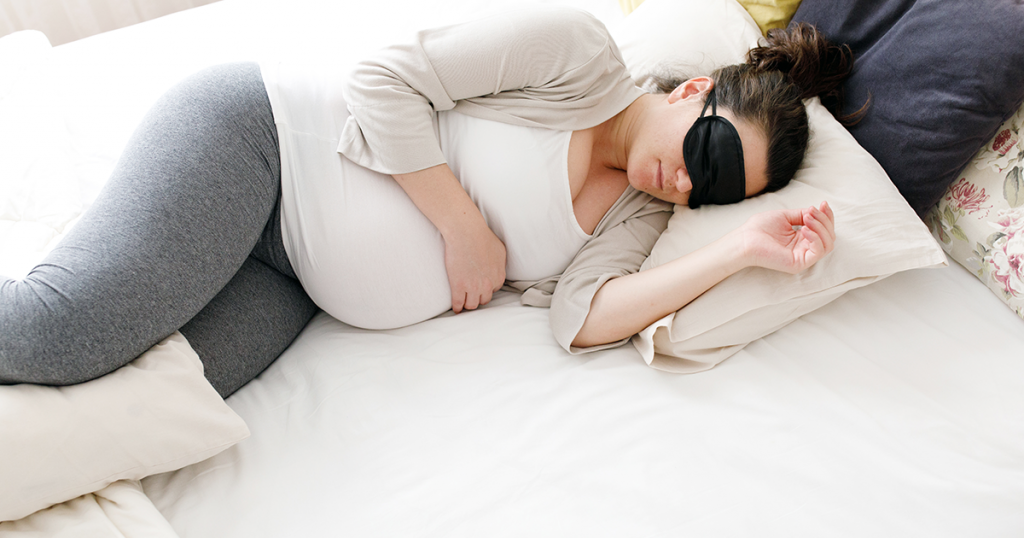 white pregnant woman sleeping with an eye mask on