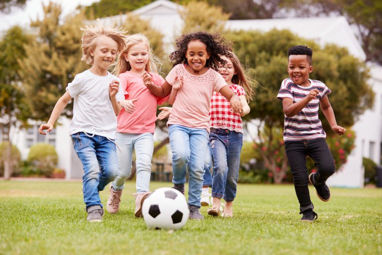 5 children running and playing soccer together.