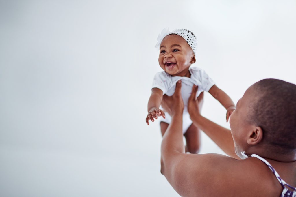 Baby girl smiling and bonding with her parent at home.