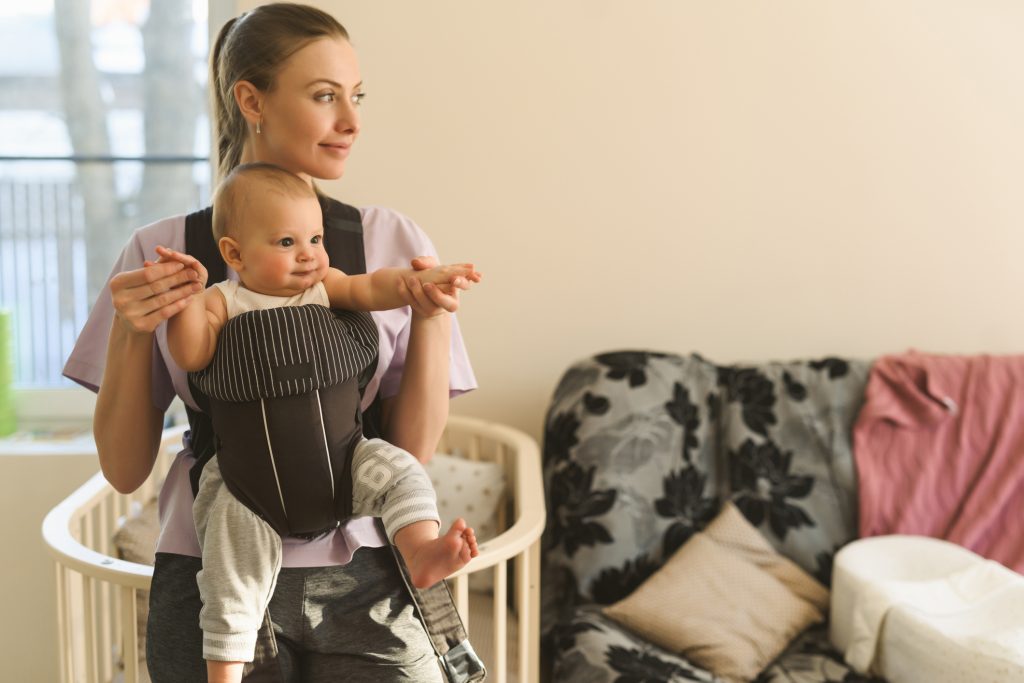 Portrait of a young mother with a child in a child carrier.