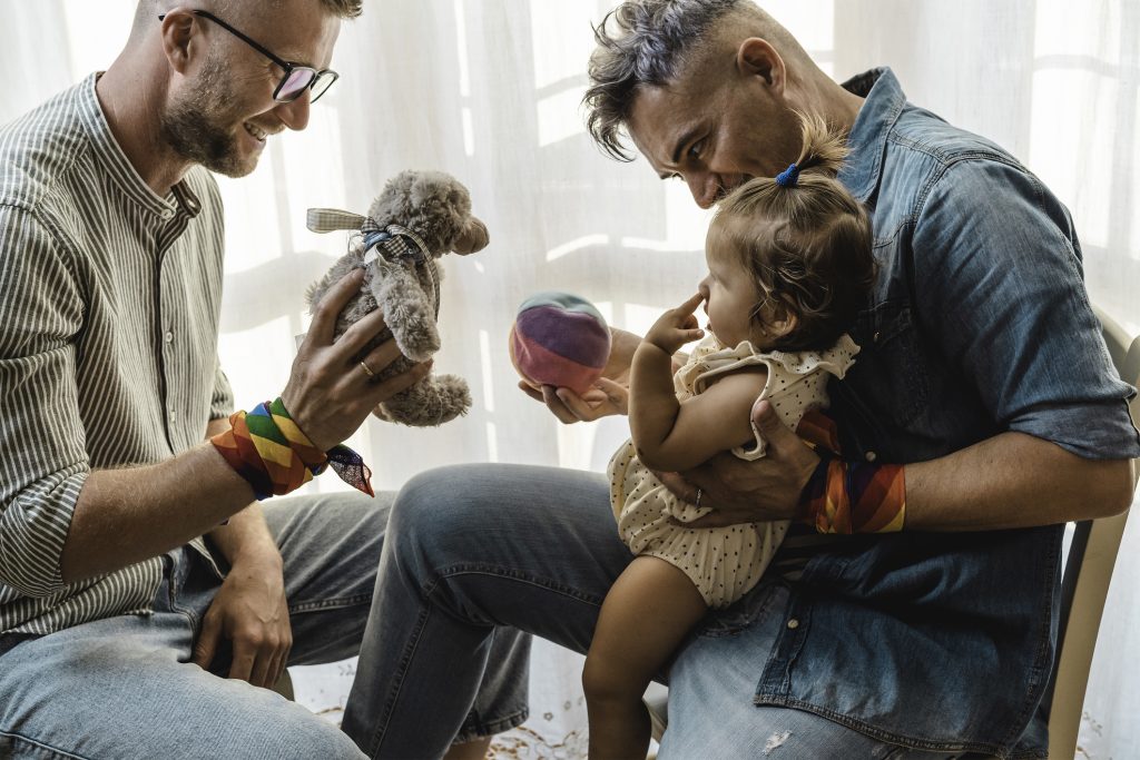 Male gay couple with adopted baby girl at home
