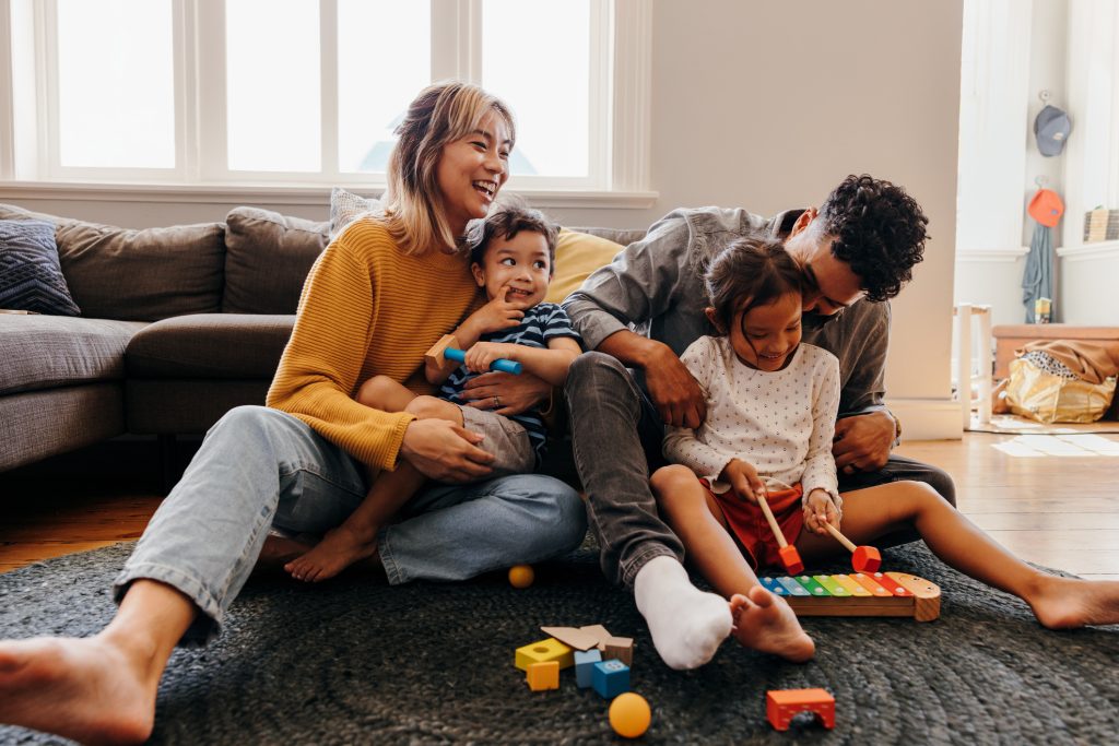 Young parents playing with their son and daughter in the living room