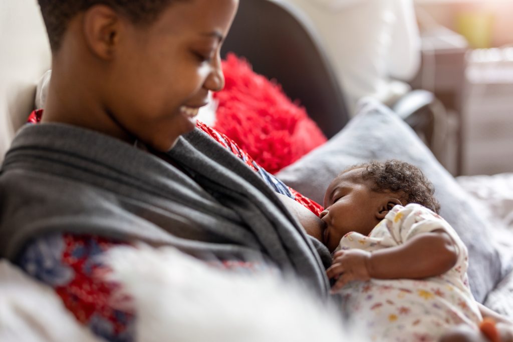 Mother breastfeeding baby at home