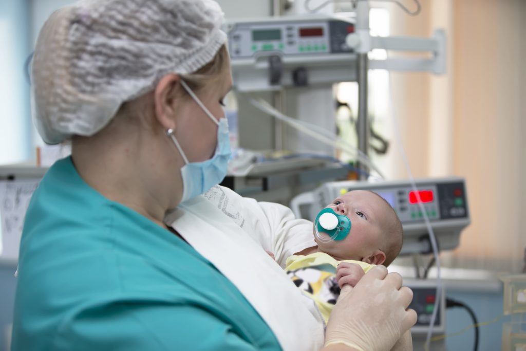 Nurse with a baby in intensive care. Newborn baby in the hospital.
