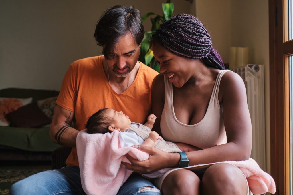 Portrait of a couple with a newborn in arms at home
