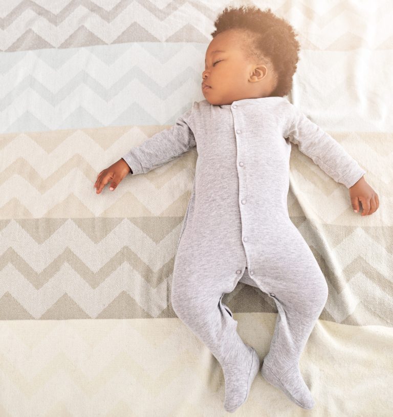 High angle shot of a little baby boy sleeping on a bed