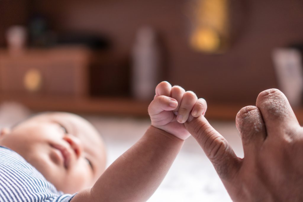 Newborn baby holding on to his parent's finger