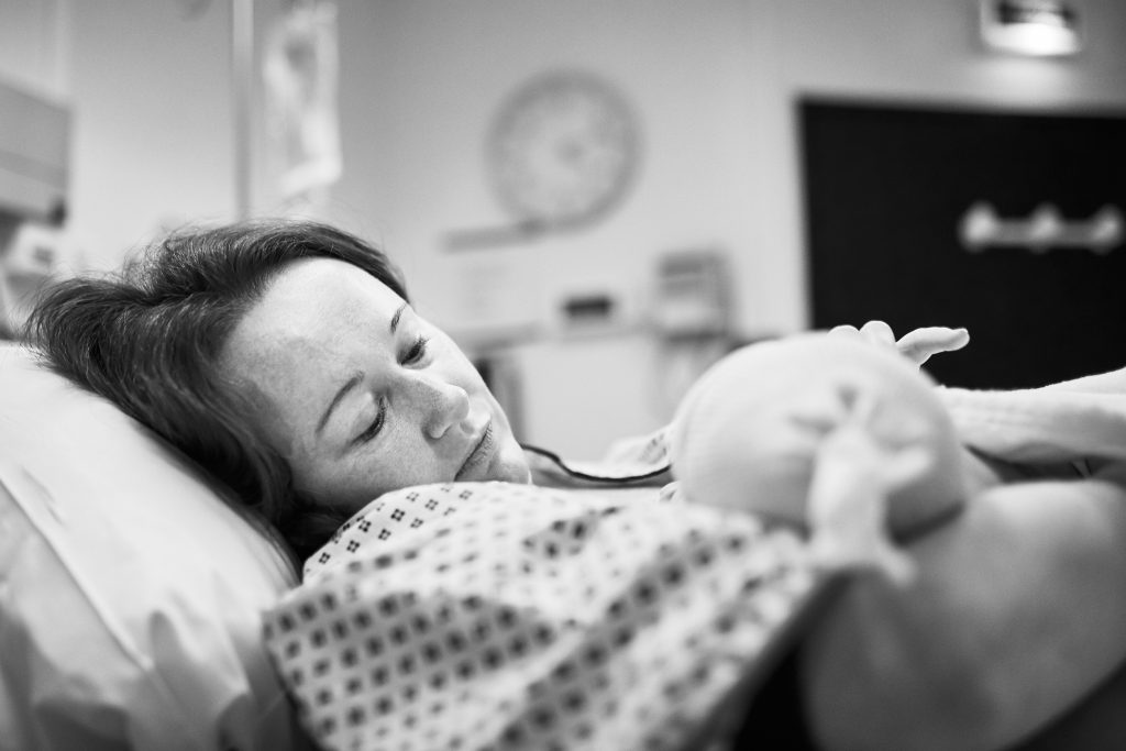 Black and white shot of mother holding her newborn baby right after delivery.
