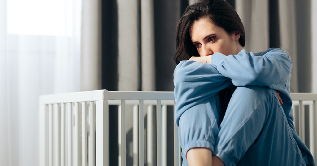 sad woman next to an empty crib