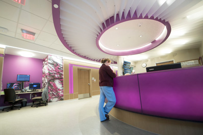 Photograph shows a nurse standing at an information desk at the St. Paul location.